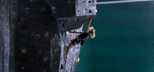 Una mujer joven escala en el rocódromo de Ansoáin